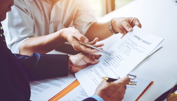 Two individuals reviewing a contract agreement