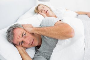 Man covering his ears next to snoring wife