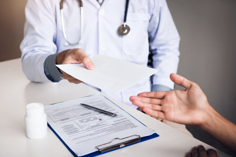 a doctor handing over a piece of paperwork