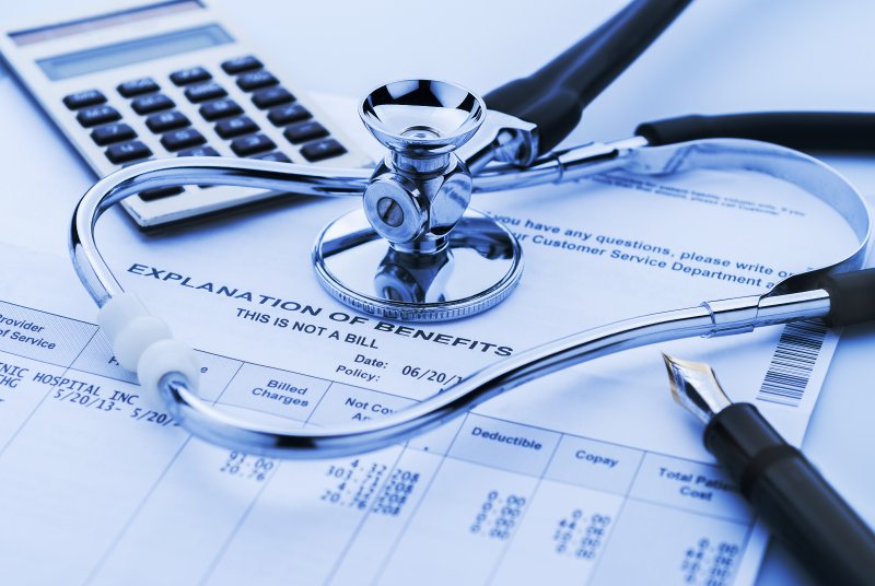 a stethoscope, calculator, pen, and explanation of benefits form 